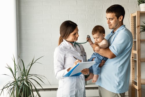 padre sosteniendo a su hijo pequeño en una consulta médica